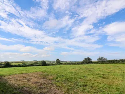 a field of grass with a blue sky with clouds at The Old Cows House in Helston