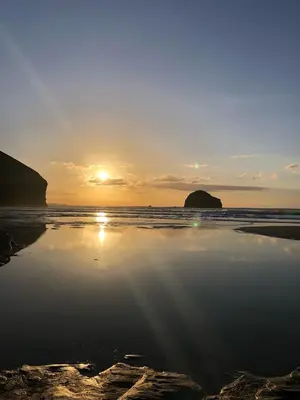 a sunset on a beach with the sun setting at Copthorne - Tintagel in Tintagel