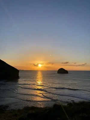 a sunset over the ocean with the sun setting at Copthorne - Tintagel in Tintagel