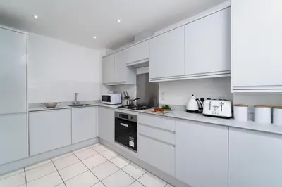 a white kitchen with white cabinets and appliances at Honeysuckle Cottage, Lelant in Uny Lelant