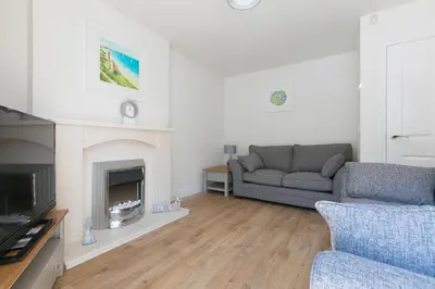 a living room with a couch and a fireplace at Honeysuckle Cottage, Lelant in Uny Lelant