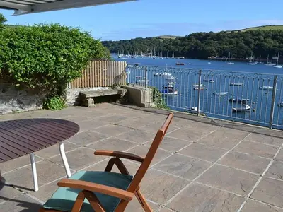 a patio with a table and a chair and water at Roadstead in Fowey