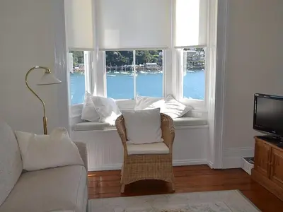 a living room with a couch and a chair and two windows at Roadstead in Fowey