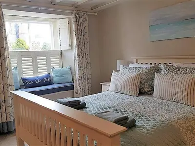 a bedroom with a large bed and a window at Below Deck in Fowey