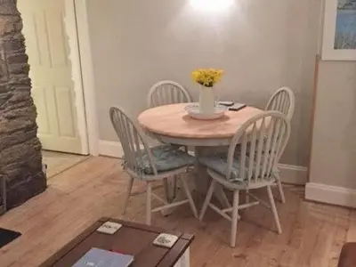 a table with chairs and a vase of flowers on it at Below Deck in Fowey