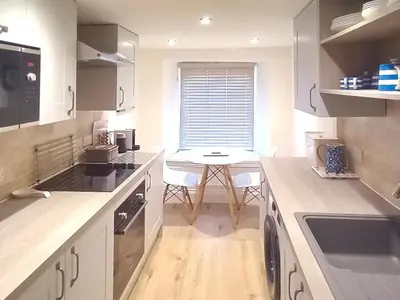a kitchen with white cabinets and a table in it at Below Deck in Fowey