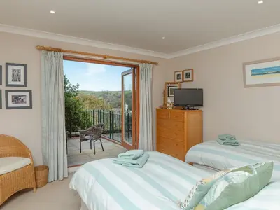 a bedroom with two beds and a balcony at Chyandour in Fowey