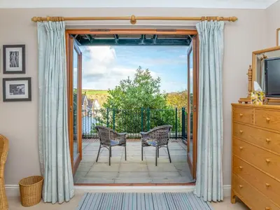 a room with a door open to a patio with two chairs at Chyandour in Fowey