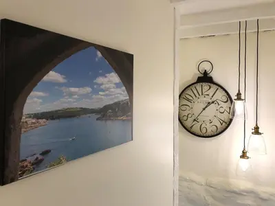 a clock hanging on a wall next to a painting at Cider Press Cottage in Fowey