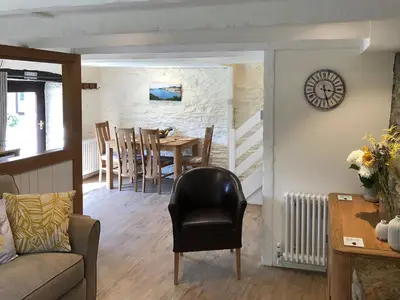 a living room with a table and a chair at Cider Press Cottage in Fowey