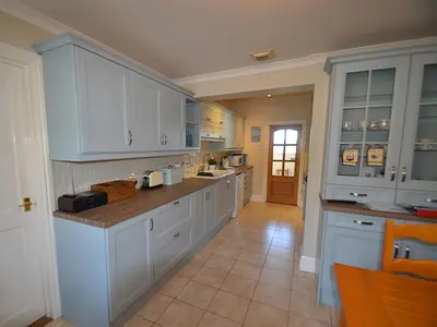a large kitchen with white cabinets and a tile floor at Riverview in Fowey