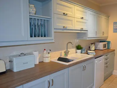 a kitchen with white cabinets and a sink at Riverview in Fowey