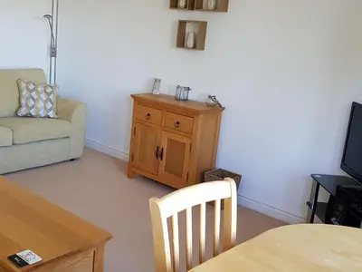a living room with a couch and a chair and a table at Meadowside Apartment in Fowey