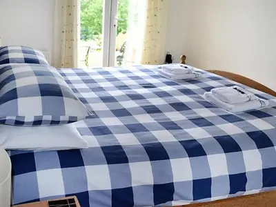 a blue and white checkered bed with two towels on it at Meadowside Apartment in Fowey