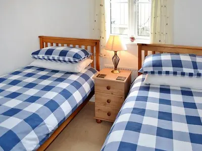 a bedroom with two beds and a lamp on a night stand at Meadowside Apartment in Fowey