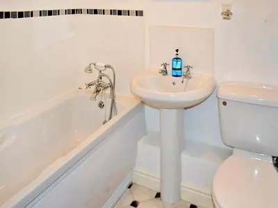 a bathroom with a sink and a toilet and a tub at Meadowside Apartment in Fowey