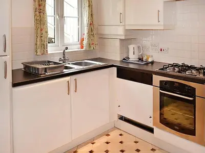 a kitchen with white cabinets and a sink at Meadowside Apartment in Fowey