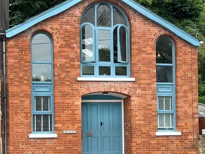 a brick building with a blue door and two windows at St Monicas in Fowey