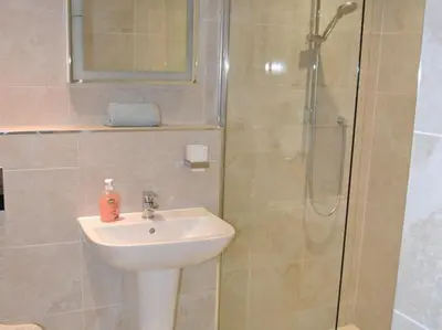 a bathroom with a sink and a shower with a glass door at St Monicas in Fowey