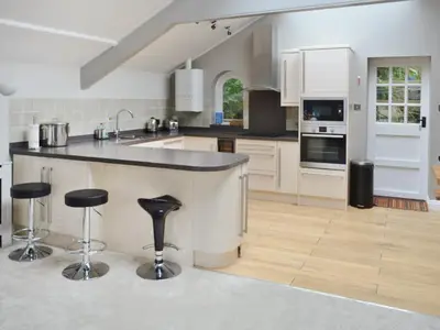 a kitchen with a counter and two bar stools at St Monicas in Fowey