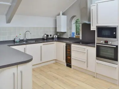 a kitchen with white cabinets and black counter tops at St Monicas in Fowey