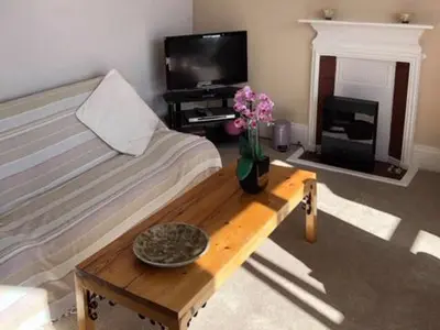 a living room with a bed and a table with flowers at St Catherines Court No 7 in Fowey