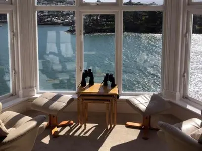 a room with a table in front of a large window at St Catherines Court No 7 in Fowey