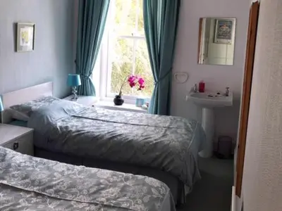 a bedroom with two beds and a sink and a window at St Catherines Court No 7 in Fowey