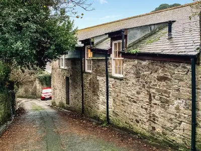 an old stone house with a car parked next to it at Rosie Cottage in Fowey