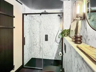 a bathroom with a shower with a glass door at Rosie Cottage in Fowey