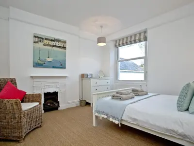 a bedroom with a bed and a chair and a window at Anchor Loft in Fowey