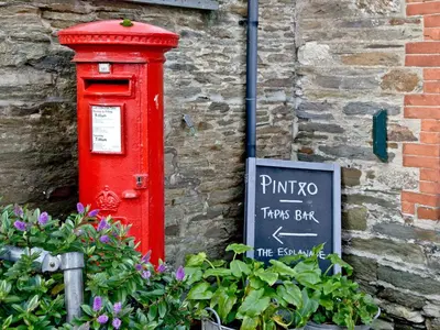 a red post box next to a brick wall at Anchor Loft in Fowey