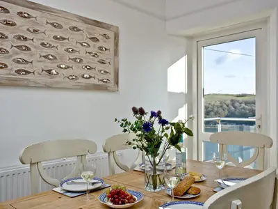 a dining room table with a vase of flowers on it at Anchor Loft in Fowey