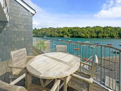 a table and chairs on a deck with a view of the water at Middle Deck in Fowey
