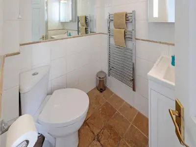 a white bathroom with a toilet and a sink at Middle Deck in Fowey