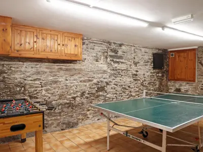a ping pong table in a room with a stone wall at Middle Deck in Fowey