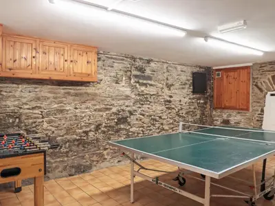 a ping pong table in a room with a stone wall at Tarquins in Fowey