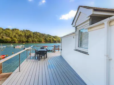 a deck with a table and chairs on a boat at Tarquins in Fowey