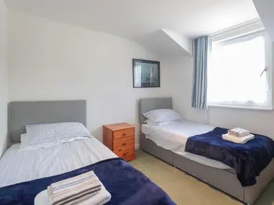 a bedroom with two beds and a window at Tarquins in Fowey