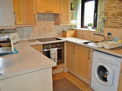 a kitchen with a sink and a washing machine at Mill Cottage in Fowey