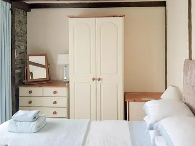 a bedroom with a bed and a dresser with a mirror at Mill Cottage in Fowey