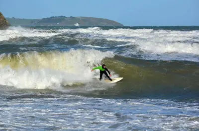 a man riding a wave on a surfboard in the ocean at Waves at The Beach House in Falmouth
