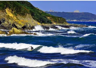 a person riding a wave on a surfboard in the ocean at Waves at The Beach House in Falmouth