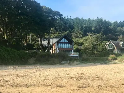 a house sitting on the side of a beach at Waves at The Beach House in Falmouth
