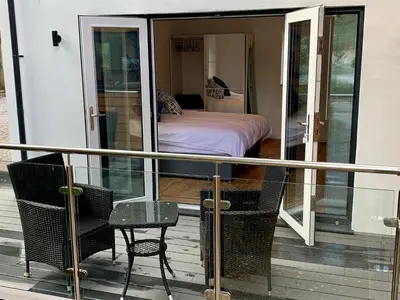 a balcony with a bedroom and a bed and chairs at Waves at The Beach House in Falmouth