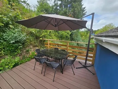 a table and chairs with an umbrella on a deck at Trengilly Wartha Inn in Constantine