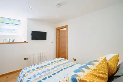 a bedroom with a couch and a tv on the wall at Finest Retreats - Luxury Holiday Let in Porthleven, Sleeping 2 in Porthleven