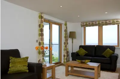 a living room with a couch and a table at South Fistral Seaview 2-bed Apartment in Newquay