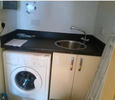 a kitchen with a sink and a washing machine at South Fistral Seaview 2-bed Apartment in Newquay