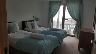 a bedroom with two beds and a window with a view at South Fistral Seaview 2-bed Apartment in Newquay